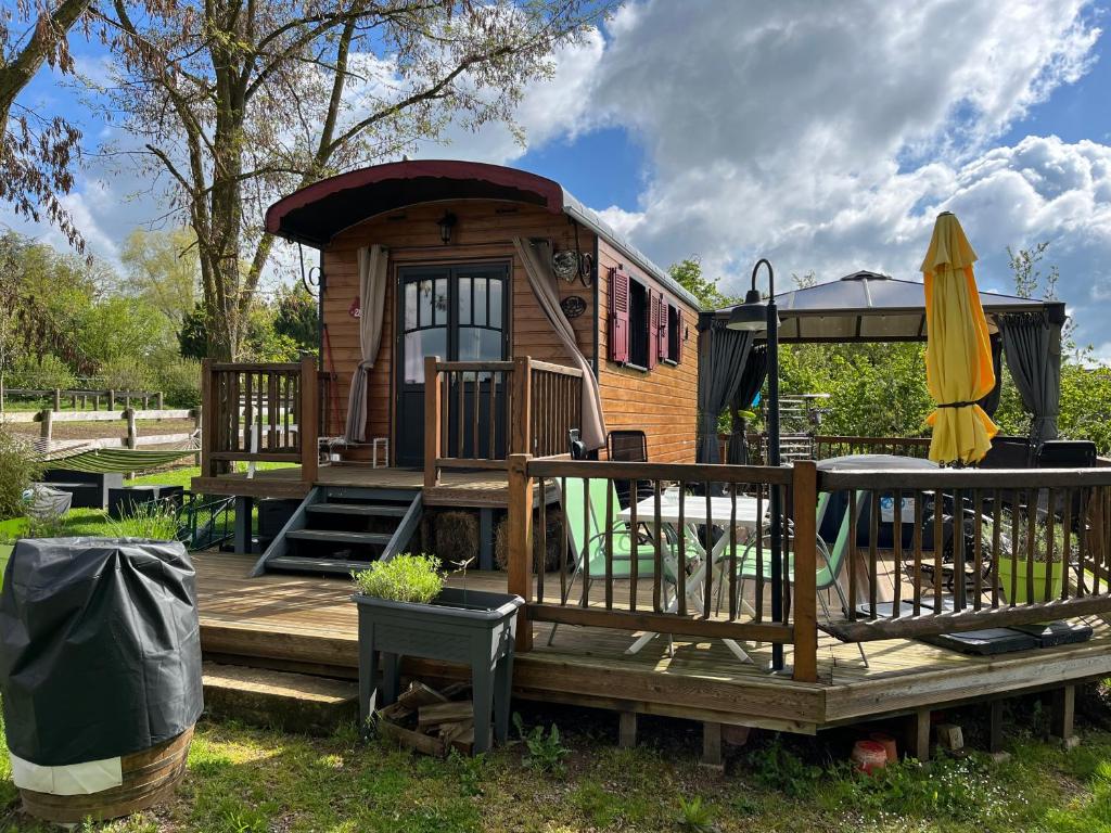 une petite maison avec une terrasse et un parasol dans l'établissement Roul'hôtes évasion, à Clamerey