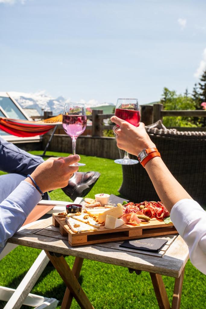 deux personnes tenant des verres de vin à une table de pique-nique dans l'établissement Hôtel Au Chamois d'Or by Les Etincelles, à L'Alpe-d'Huez