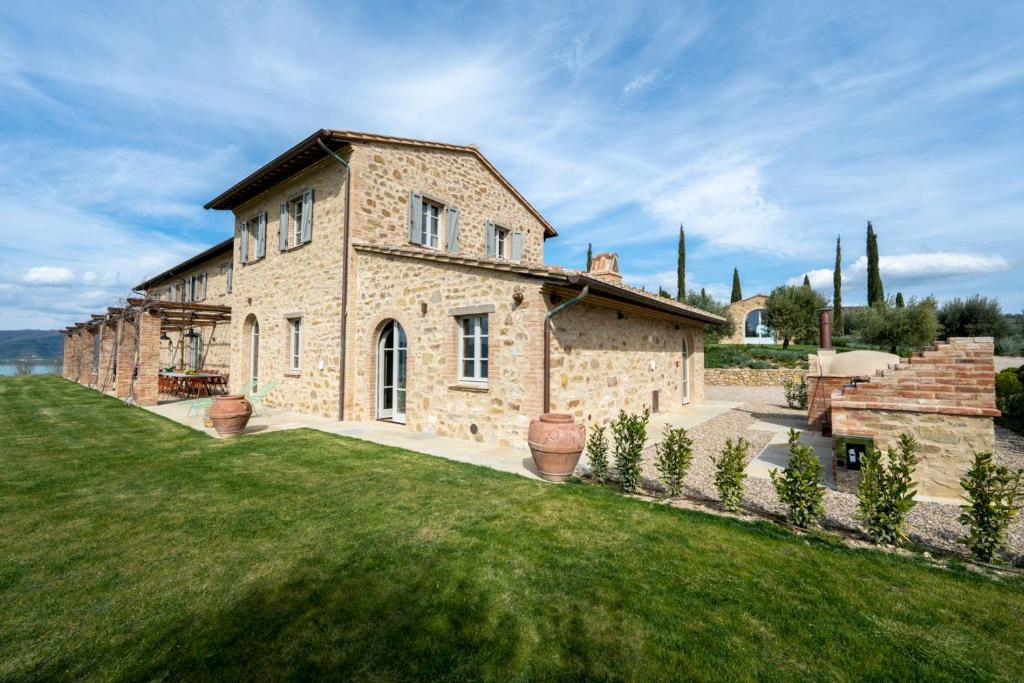 une grande maison en pierre avec une pelouse verte dans l'établissement Battisole Luxury Villa by Great Stays, à Monte del Lago