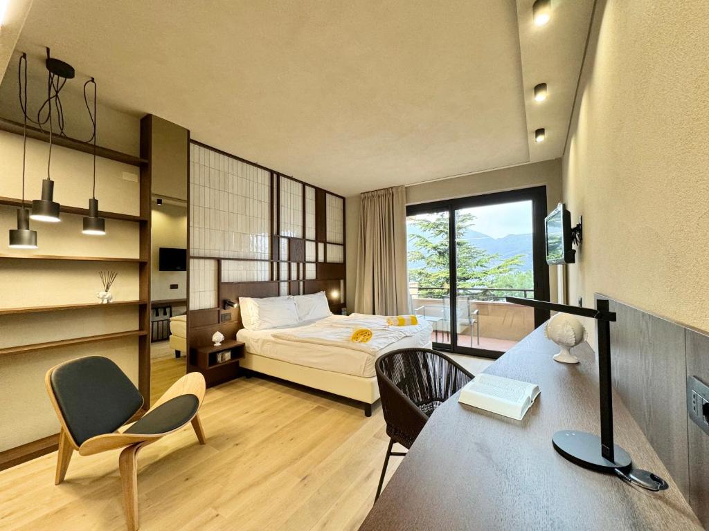 une chambre avec un lit, un bureau et des chaises dans l'établissement Hotel Du Lac - Relax Attitude Hotel, à Brenzone