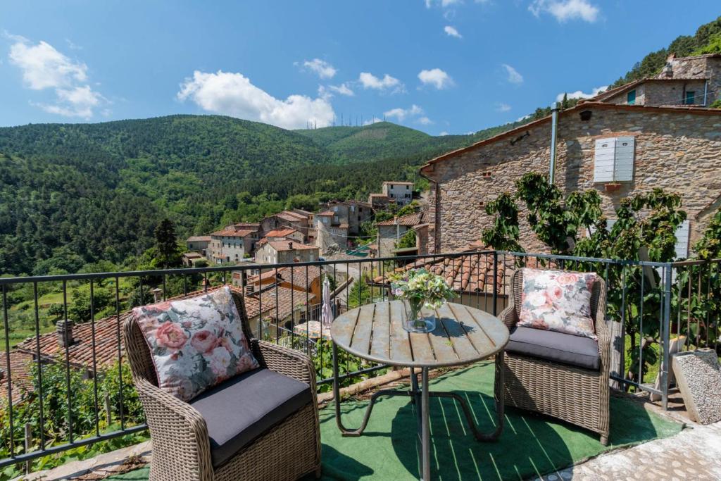 d'un balcon avec une table, des chaises et des montagnes. dans l'établissement Cottage Gigi, Smart Convenient Stone Village House, à Ruota