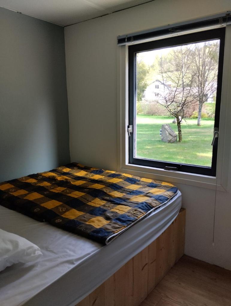un lit dans une chambre avec une fenêtre dans l'établissement Chalet 9 personnes, piscine, terrasse, à Saint-Maurice-sur-Moselle