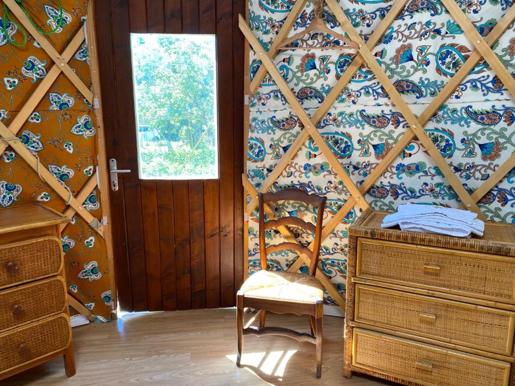 Cette chambre comprend une chaise, une commode et une fenêtre. dans l'établissement Yourte à La Campagnette, à Montpellier