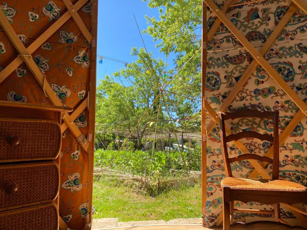 Cette chambre comprend une chaise et offre une vue sur la cour. dans l'établissement Yourte à La Campagnette, à Montpellier