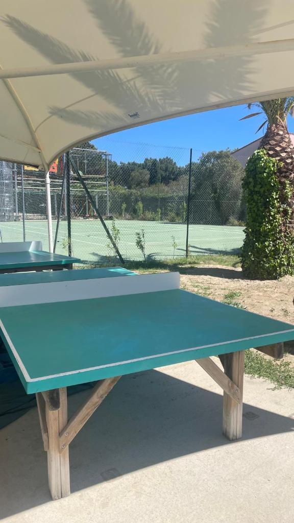 une table de ping-pong bleue devant un court de tennis dans l'établissement Mobil-home SUNSEA Camping DEL MAR, à Argelès-sur-Mer