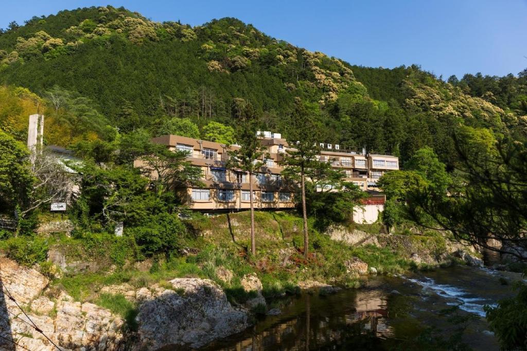 un bâtiment sur une colline à côté d'une rivière dans l'établissement Yunokaze HAZU, à Shinshiro