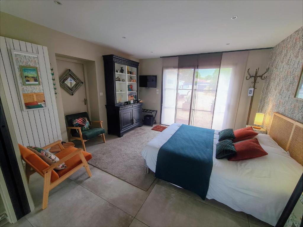 une chambre avec un grand lit et une chaise dans l'établissement Gîte à SAINT ANDRE DE LA MARCHE proche du Puy du foù, à Saint-André-de-la-Marche