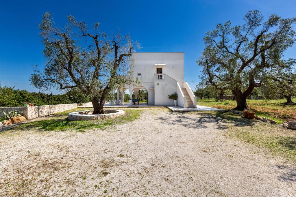 une maison blanche avec deux arbres devant elle dans l'établissement Villa Sierri by Perle di Puglia, à Specchiolla