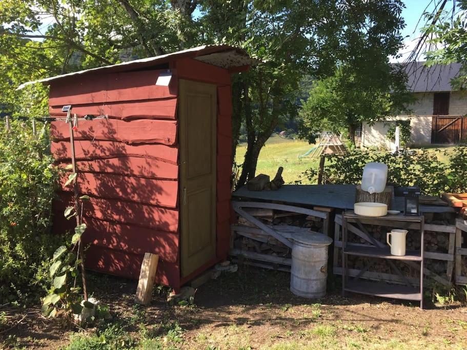 un hangar rouge avec une table dans une cour dans l'établissement Yourte de la bas, à Curienne