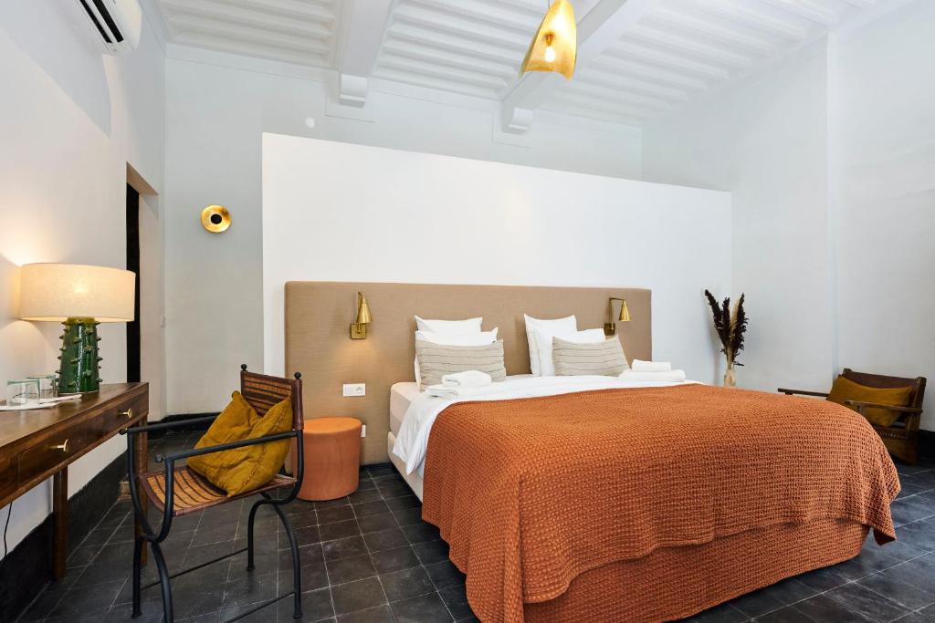 - une chambre avec un grand lit, un bureau et une chaise dans l'établissement Riad Dar Nakous, à Marrakech