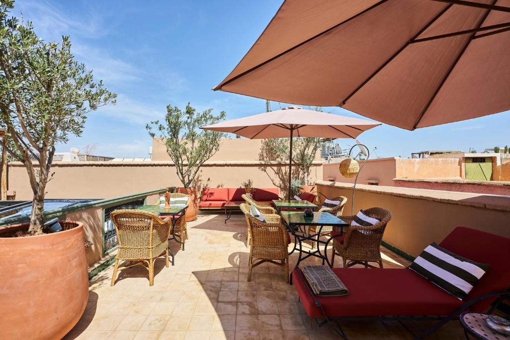 un patio avec tables, chaises et un parasol dans l'établissement Riad Dar Nakous, à Marrakech