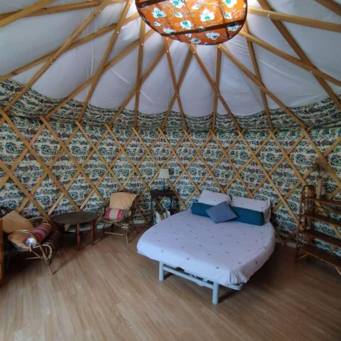 - une chambre dans une yourte avec un lit et des chaises dans l'établissement Yourte à La Campagnette, à Montpellier