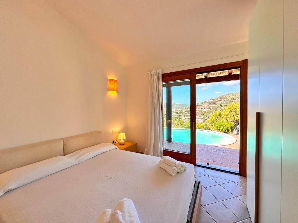 une chambre avec un lit et une vue sur une piscine dans l'établissement Villa Nais - Premium Villa, à Chia