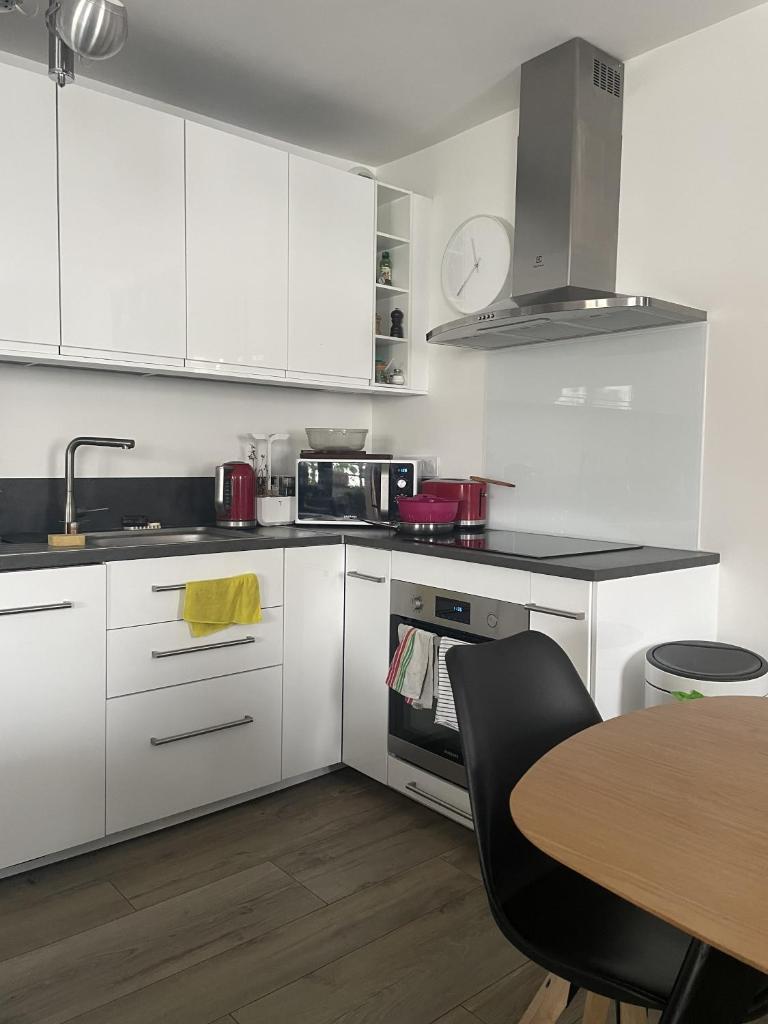 une cuisine avec des armoires blanches, une table et un évier dans l'établissement Chambre suite privée à Boulogne, à Boulogne-Billancourt