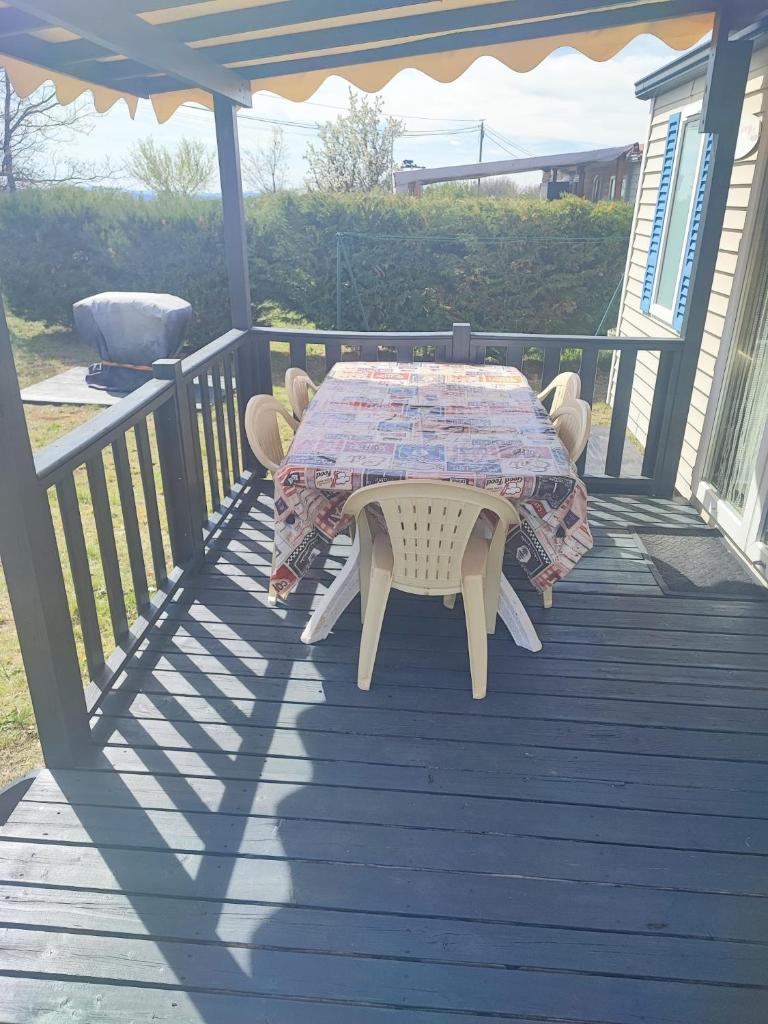 une table et des chaises assises sur une terrasse dans l'établissement Flo mobil home camping Poney trois étoiles route de Moustiers Ste Croix, à Sainte-Croix-de-Verdon