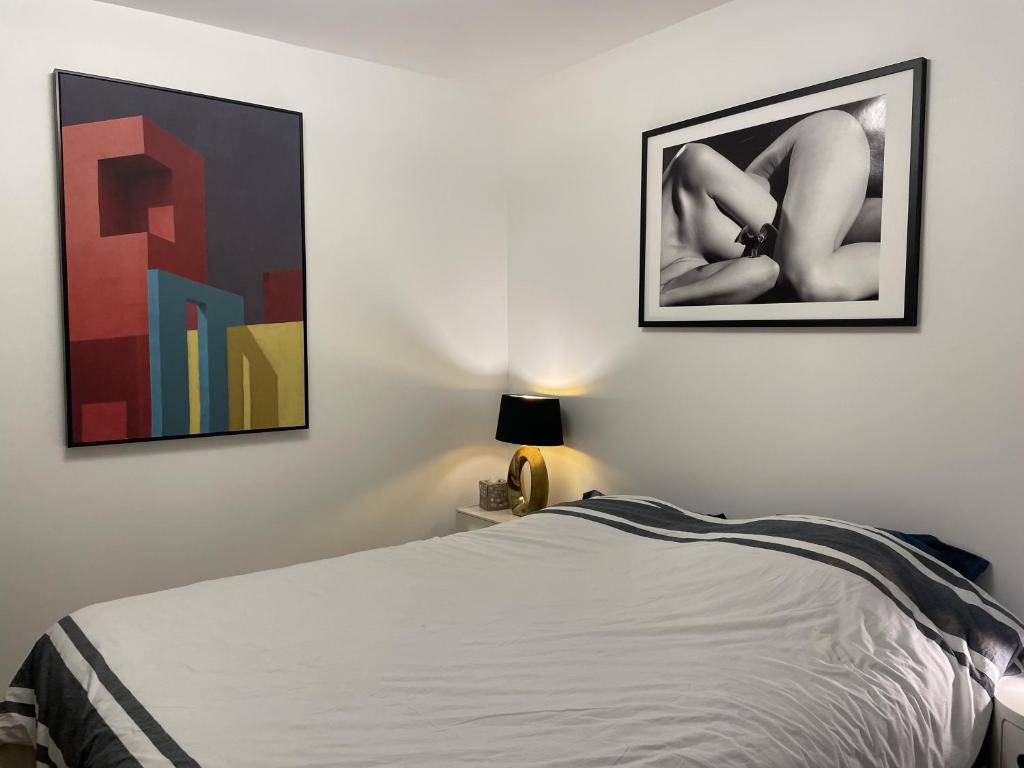 une chambre avec un lit et deux tableaux au mur dans l'établissement Chambre suite privée à Boulogne, à Boulogne-Billancourt