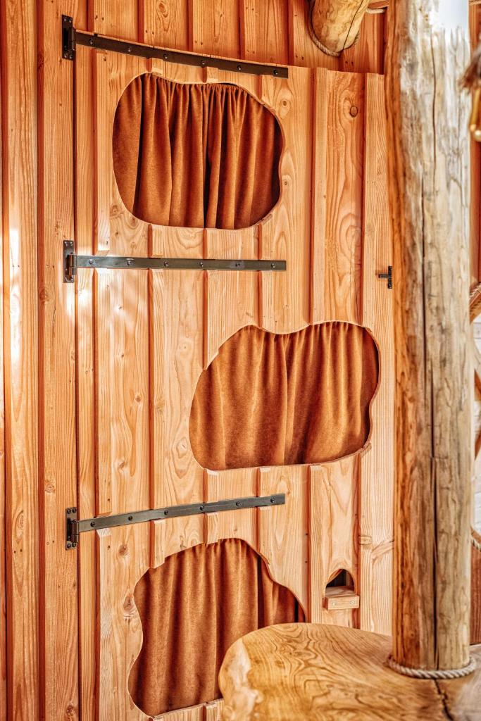 une pièce avec des murs en bois avec des rideaux et des étagères marron dans l'établissement La Cabane Korrigans, à Gommené