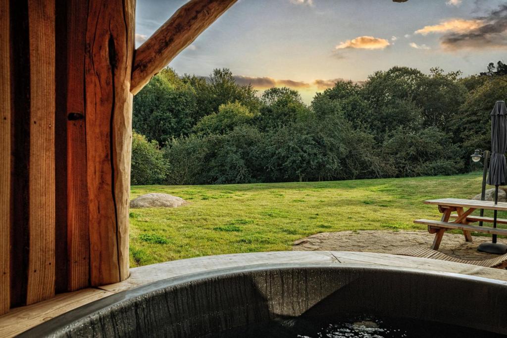 une vue depuis le porche d'une cabane en bois avec un étang dans l'établissement La Cabane Korrigans, à Gommené