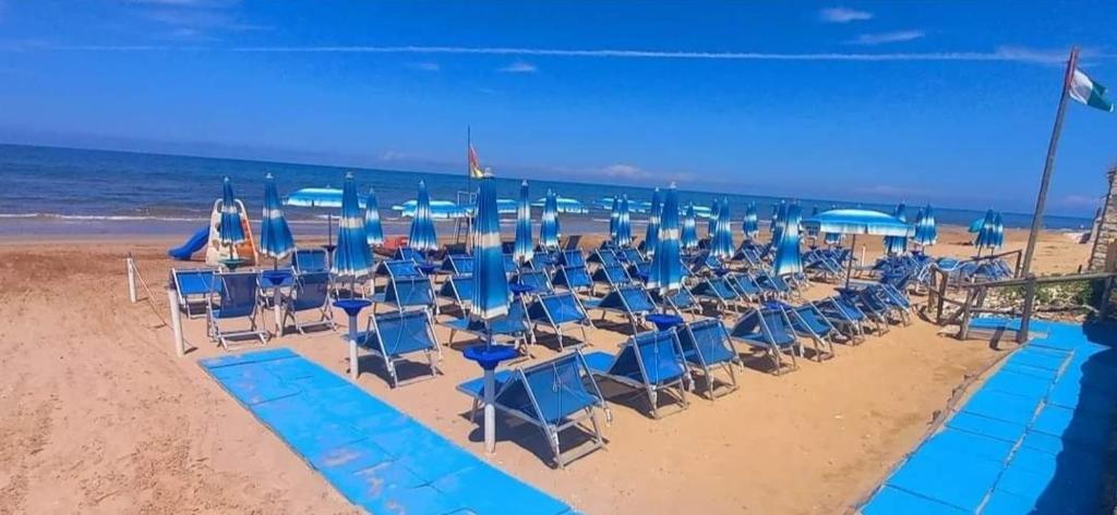 - un groupe de chaises et de parasols bleus sur une plage dans l'établissement Hotel Ristorante Sturno, à San Menaio