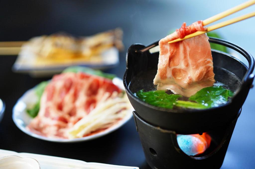 un récipient noir avec de la nourriture sur une table avec des assiettes de nourriture dans l'établissement ピーポロ乗鞍, à Matsumoto
