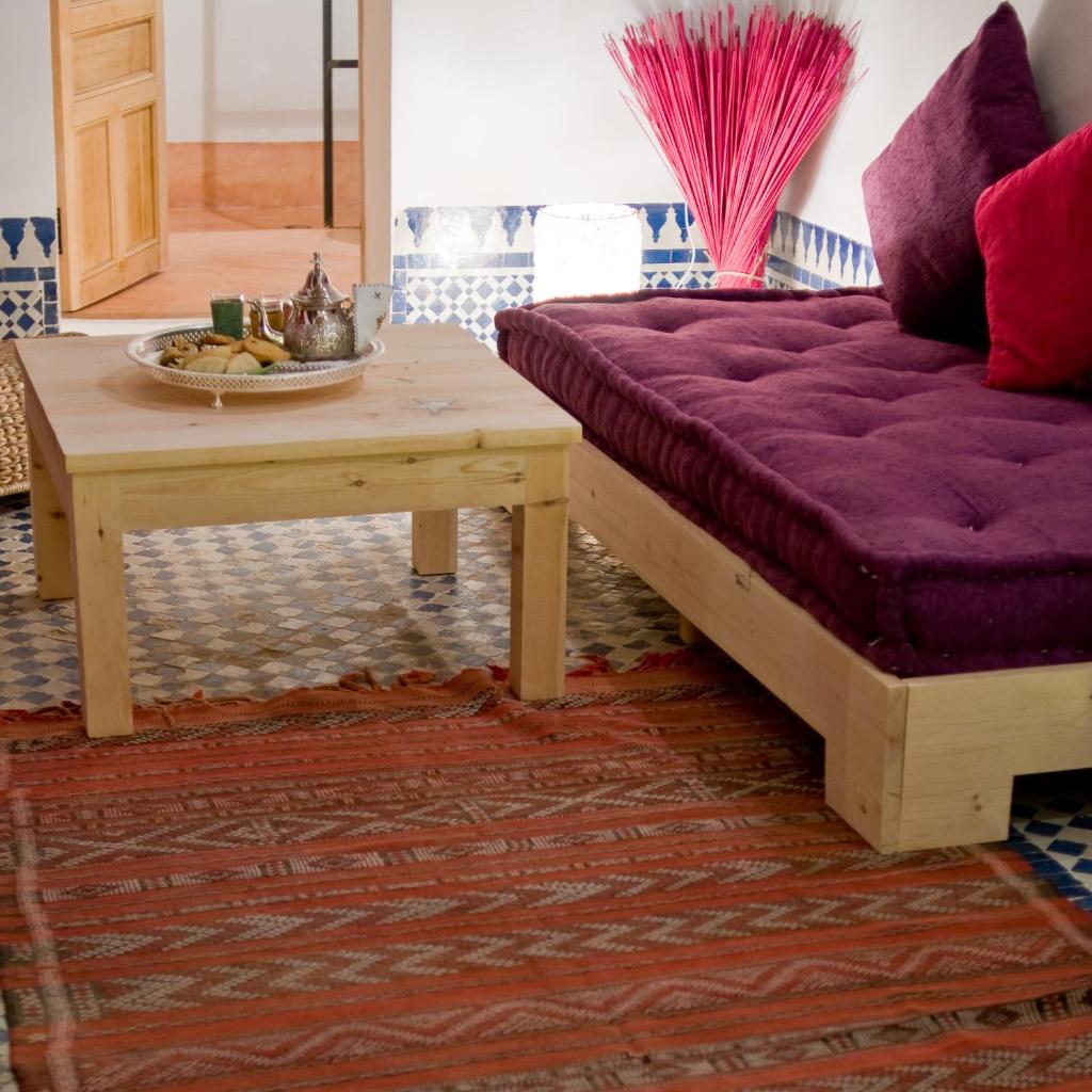 un salon avec un canapé violet et une table dans l'établissement Riad La Maison D'à Côté, à Meknès