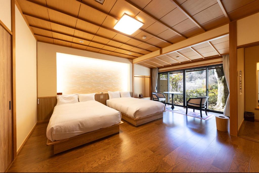une chambre avec deux lits et une grande fenêtre dans l'établissement Kawakamiya Kasuitei, à Gero