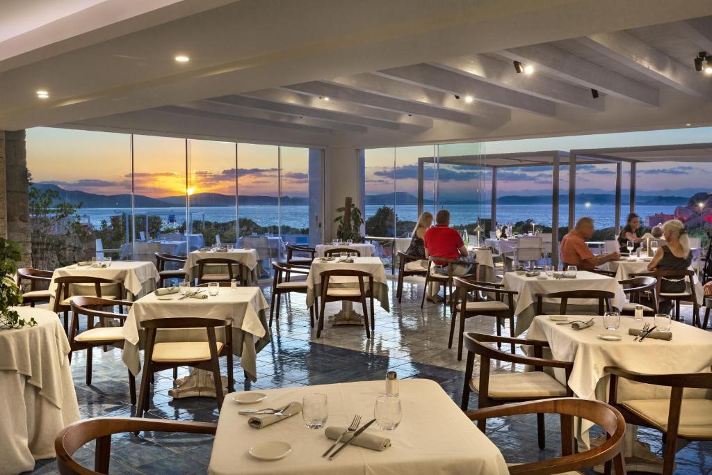 - un restaurant avec des tables et des chaises blanches offrant une vue dans l'établissement Hotel Grand Relais Dei Nuraghi, à Baja Sardinia