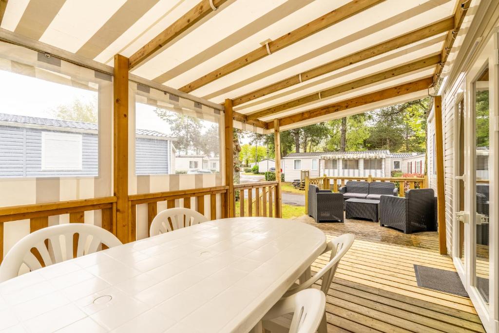 une terrasse en bois avec une table et des chaises blanches dans l'établissement Mobil-home Saint Jean de Monts, à Saint-Jean-de-Monts