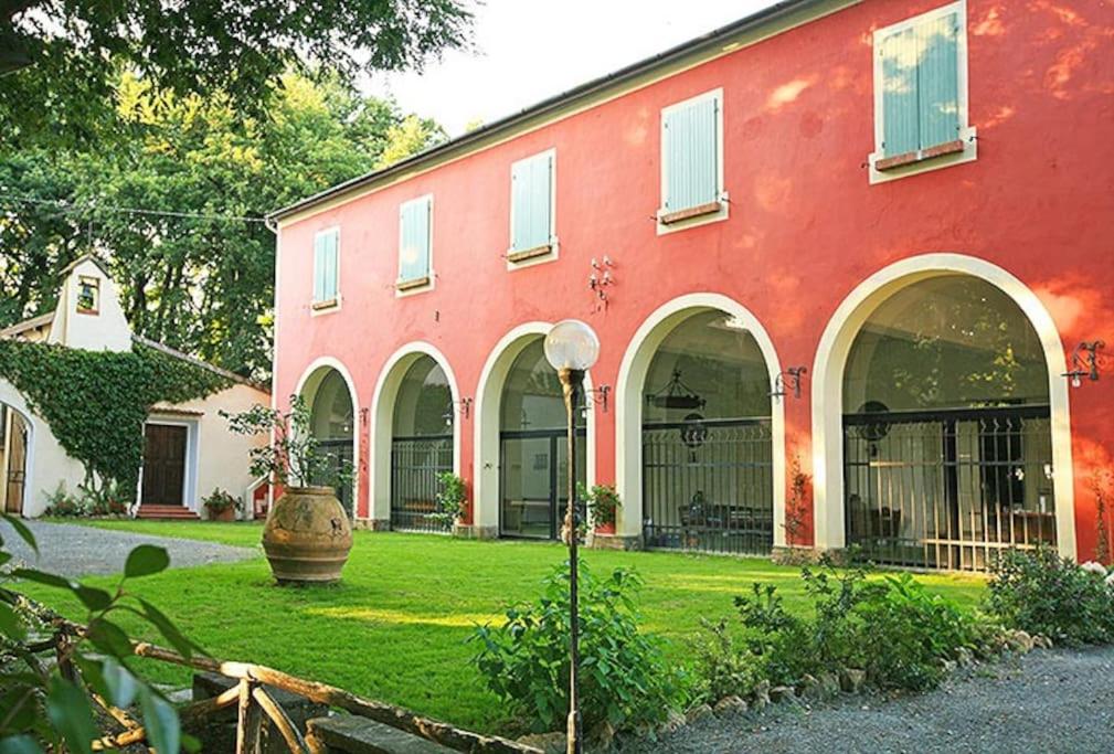 un bâtiment rouge avec une cour verdoyante devant lui dans l'établissement Tenuta la Valle Relaxing Oasis with pool in Tuascany, à Vada