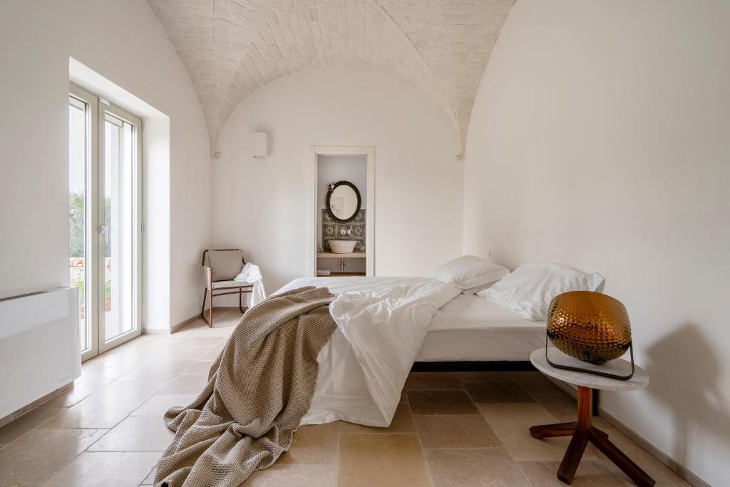 une chambre blanche avec un lit et une chaise dans l'établissement Trullo Saraceno, à Ostuni