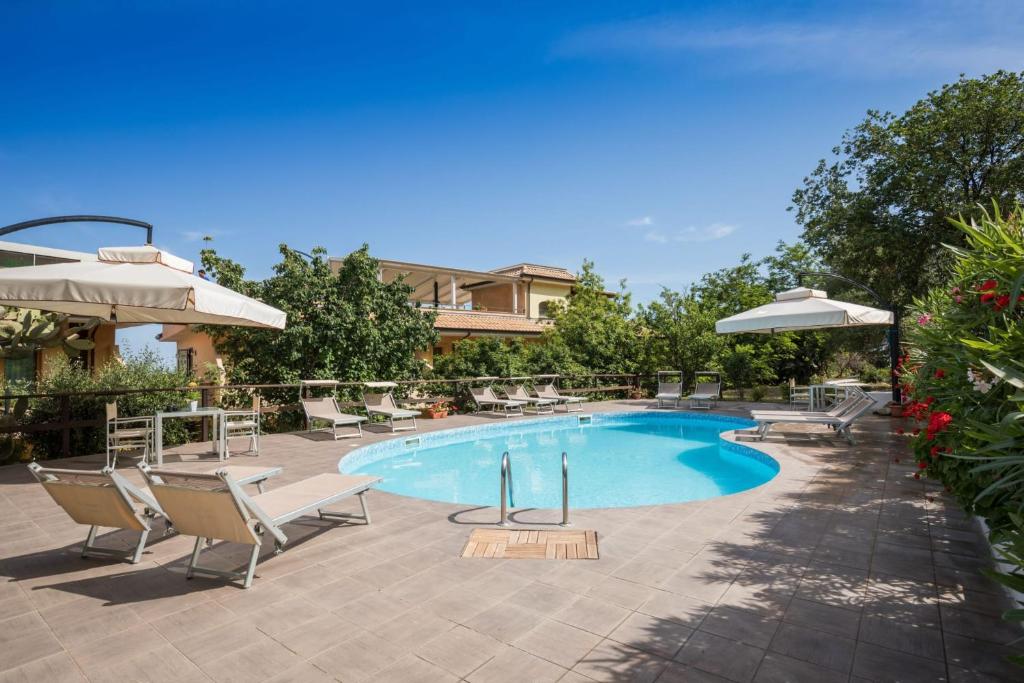 une piscine avec chaises et parasols dans une cour dans l'établissement UNICO Cannamele Escape Tropea by Life Resorts, à Parghelia