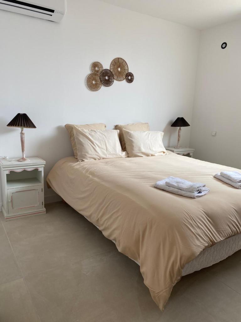 - une chambre blanche avec un grand lit et 2 tables dans l'établissement Gîtes chez Marceau, à Rasteau