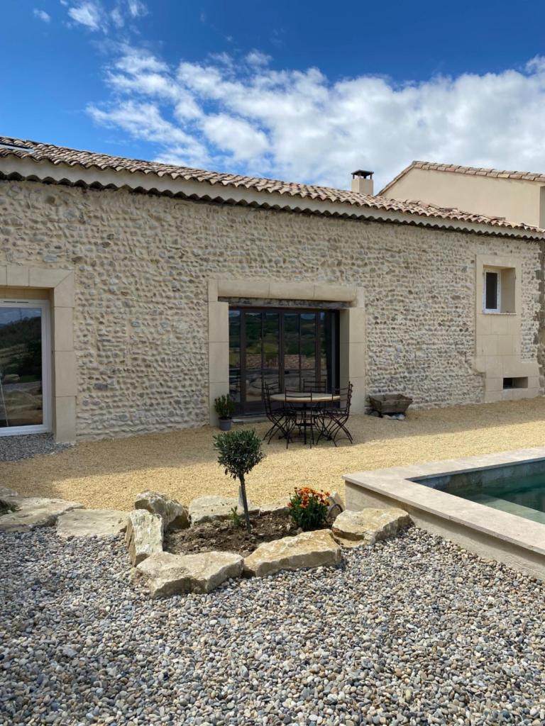 un bâtiment avec une piscine, une table et une plante dans l'établissement Gîtes chez Marceau, à Rasteau