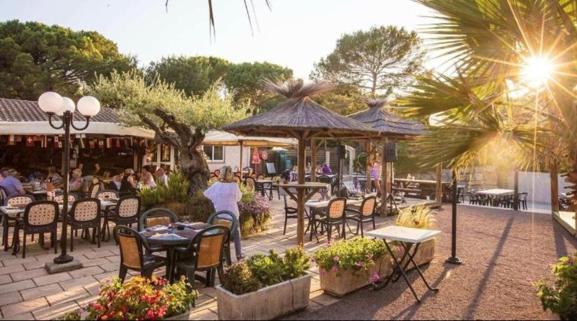 un patio avec des tables et des chaises et des personnes dans un restaurant dans l'établissement Chalet Coco, à Roquebrune-sur Argens