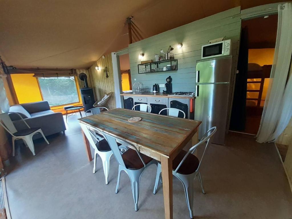une cuisine et une salle à manger avec une table et un réfrigérateur dans l'établissement Lodge Nature à Vigeois, à Vigeois
