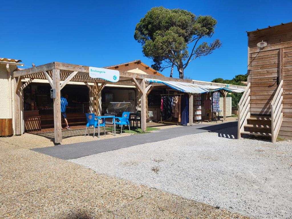 un marché avec des chaises bleues et un bâtiment dans l'établissement Mobil Home spacieux Camping Mar Estang 4*, à Canet