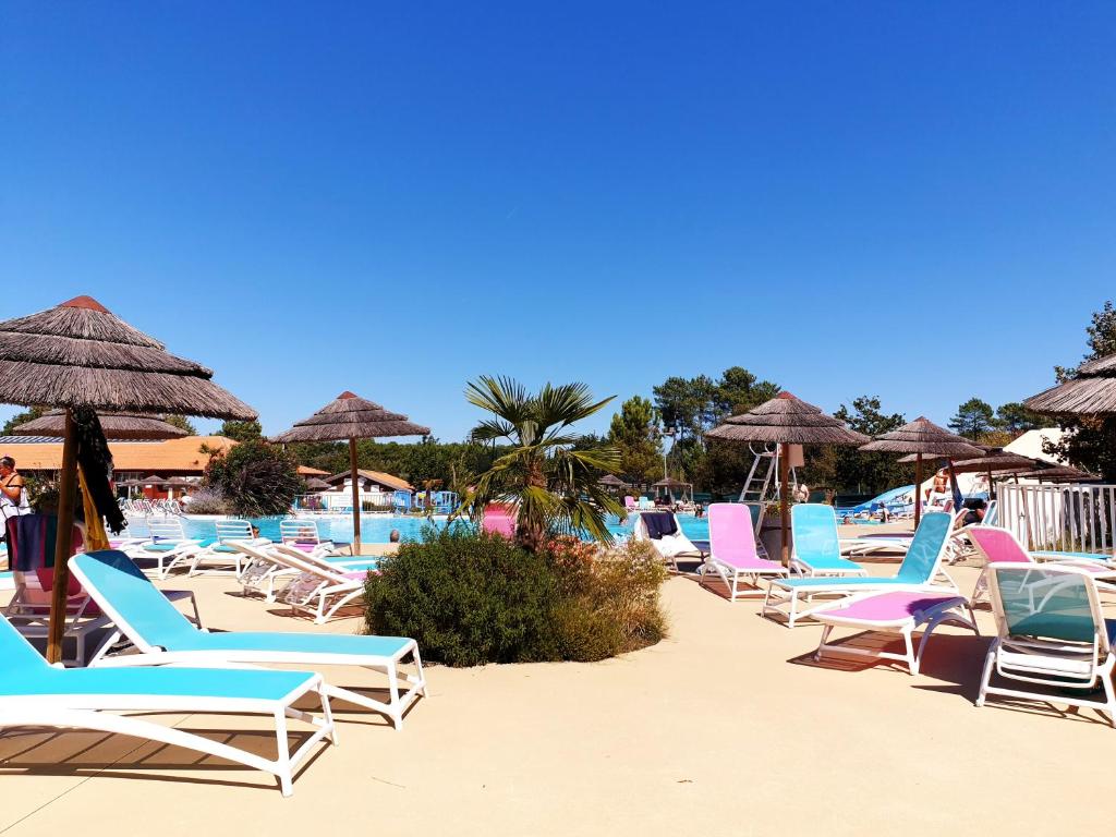 un groupe de chaises et de parasols sur une plage dans l'établissement Spacieux Mobil-home Num227 2 chambres, 2sdb à 2 pas du lac, à Gastes
