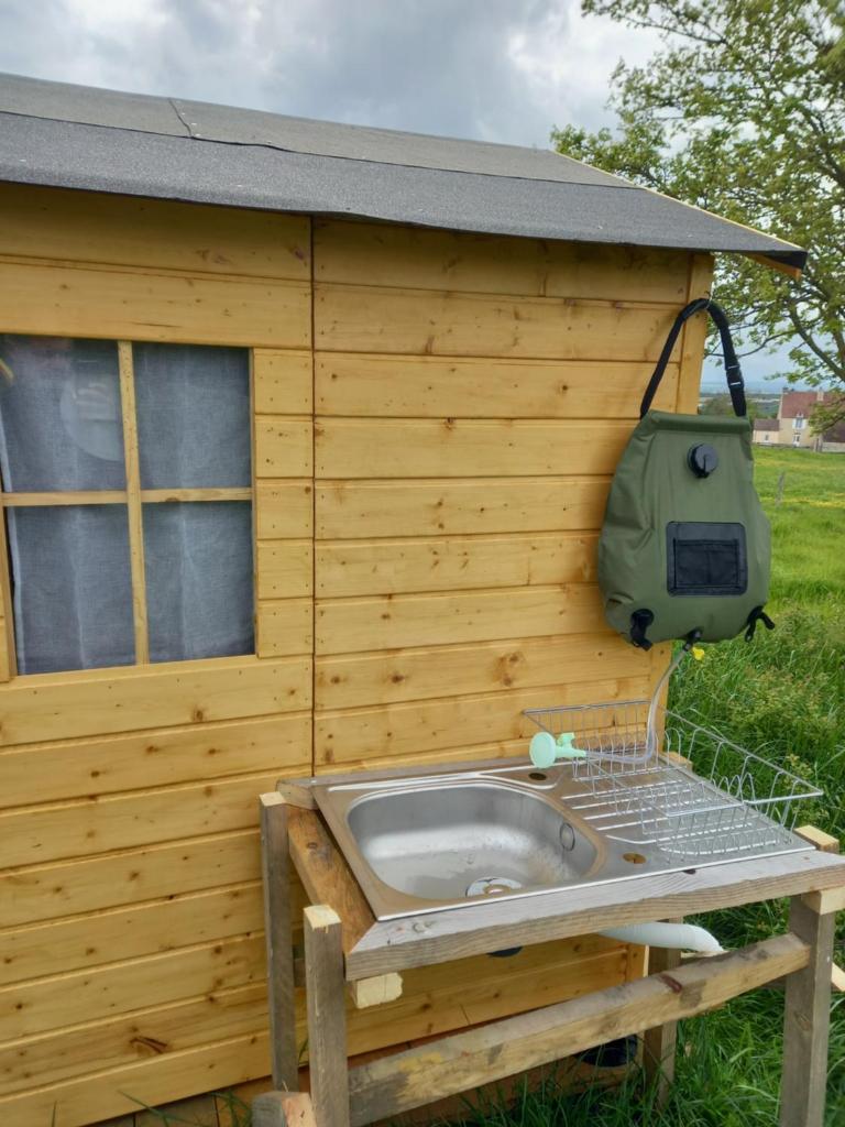 - un bâtiment avec un lavabo sur le côté dans l'établissement Yourte calvados, à Les Moutiers-en-Auge
