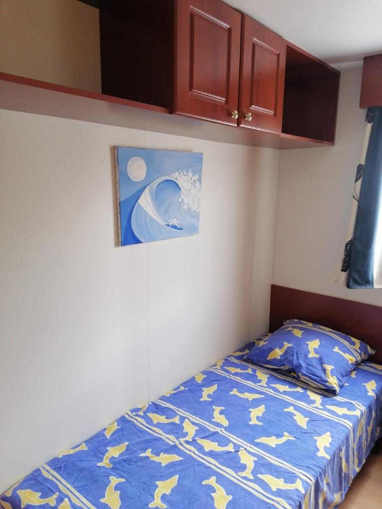 - une petite chambre avec un lit et un tableau mural dans l'établissement Mobil-home dans camping municipal, à Kermaria-Sulard