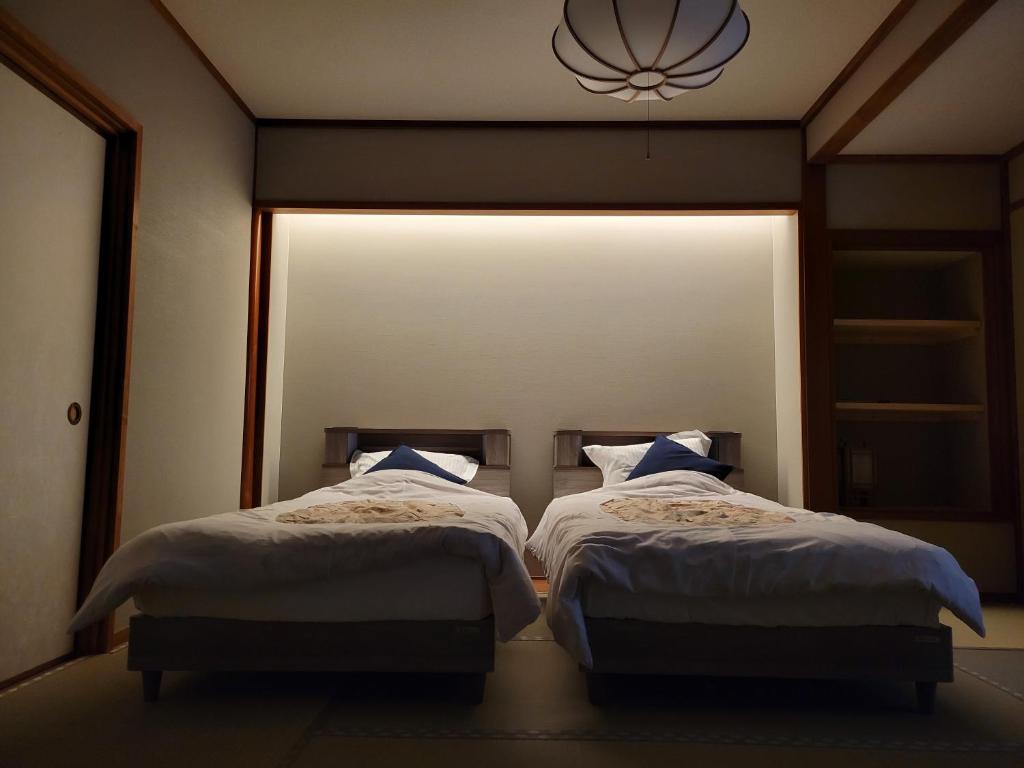 deux lits dans une chambre avec une grande fenêtre dans l'établissement Tsukimotoya Ryokan, à Toyooka