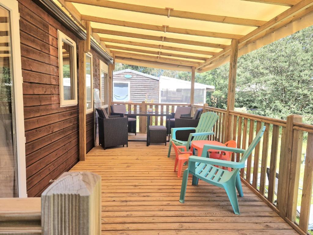une terrasse en bois avec des chaises et une table dans l'établissement Mobilhome Labenne Océan, à Labenne