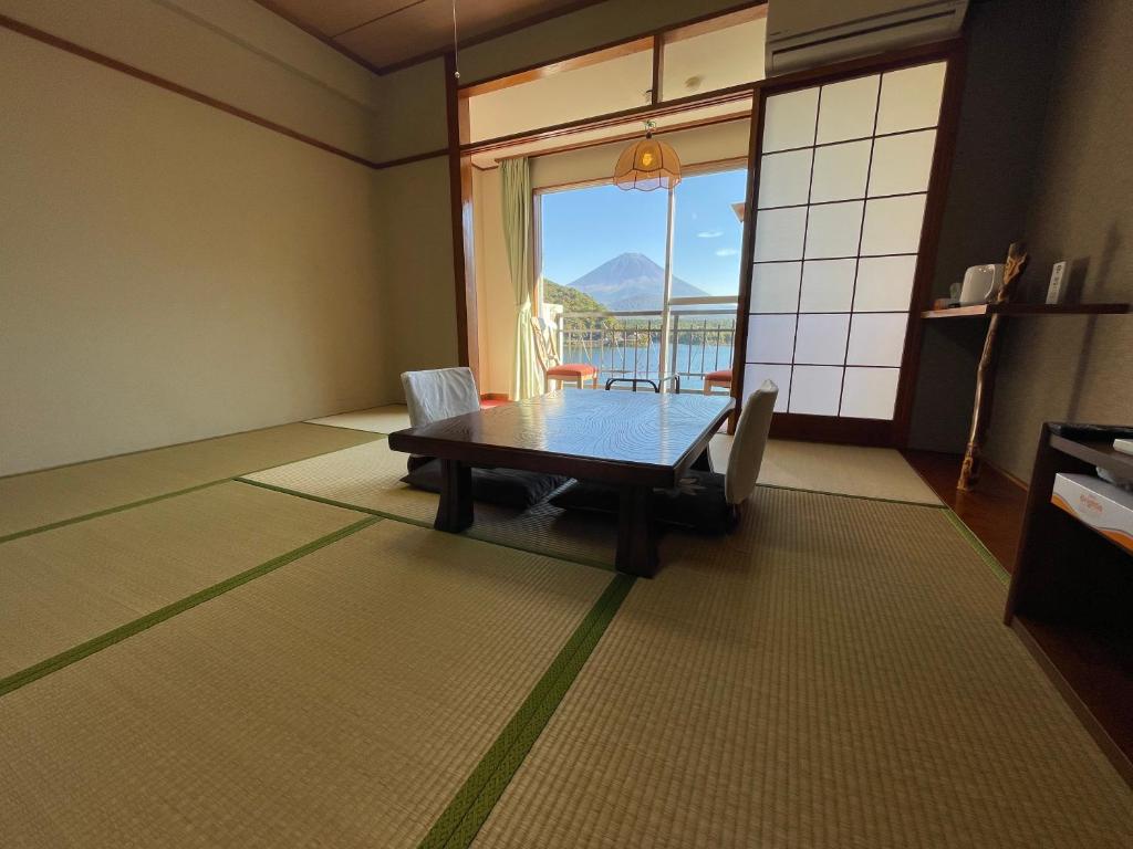 une salle à manger avec une table et une grande fenêtre dans l'établissement Shoji Lake Hotel, à Fujikawaguchiko