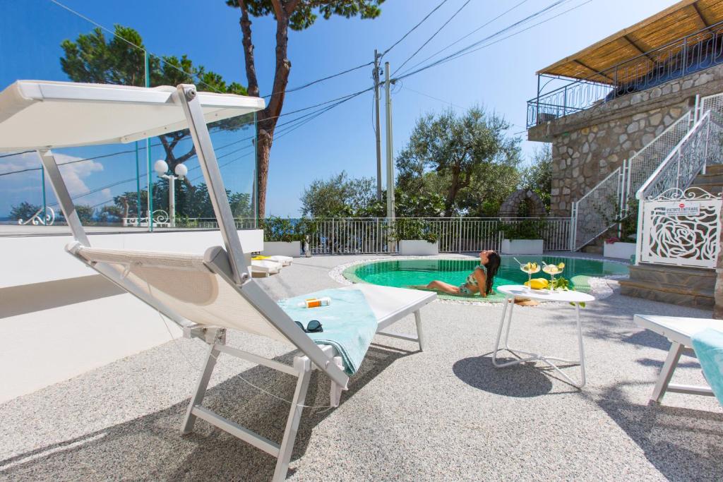 une piscine avec une chaise et un enfant y jouant dans l'établissement AMORE RENTALS - Villa Iside, à Nerano