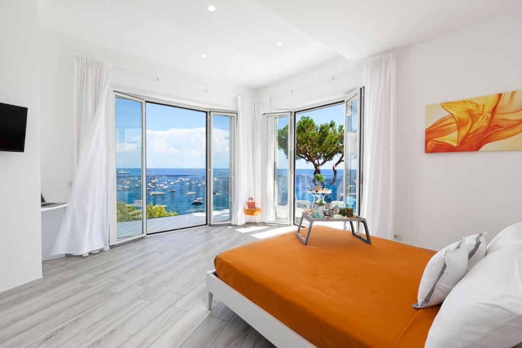 - une chambre blanche avec un lit et de grandes fenêtres dans l'établissement AMORE RENTALS - Villa Iside, à Nerano