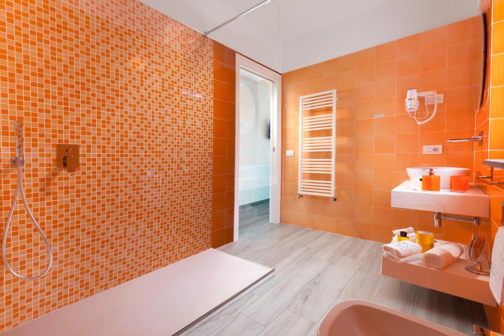 La salle de bains est pourvue de murs en carrelage orange et d'une douche. dans l'établissement AMORE RENTALS - Villa Iside, à Nerano