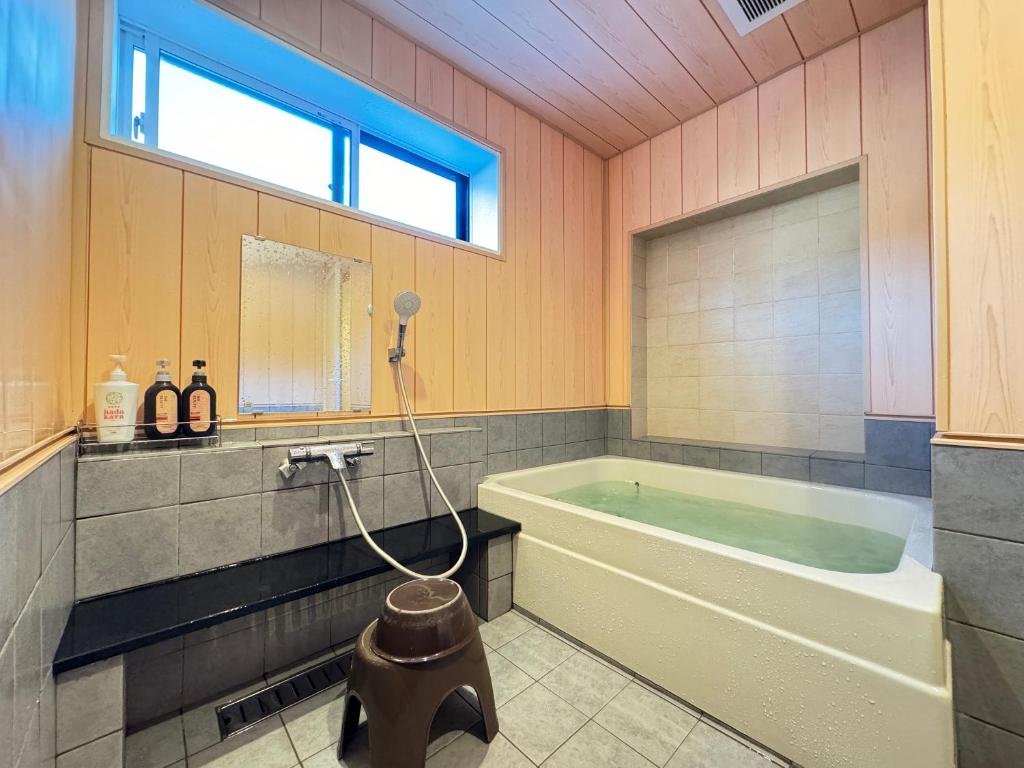 La grande salle de bains est pourvue d'une baignoire et d'une fenêtre. dans l'établissement Shiroyamasou, à Asahi