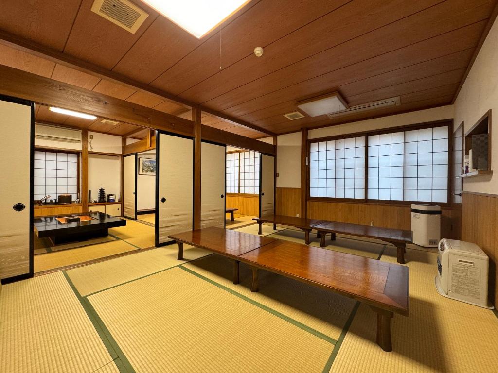 Cette grande chambre dispose d'une table en bois et de fenêtres. dans l'établissement Shiroyamasou, à Asahi
