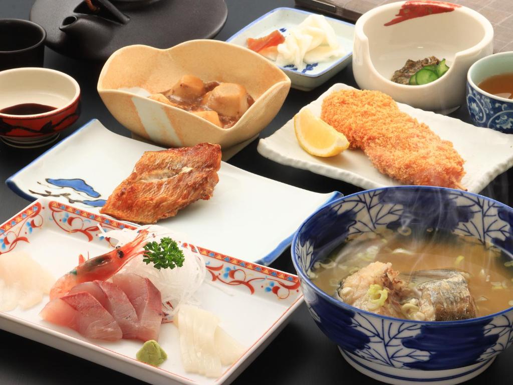 - une table avec des assiettes de nourriture et des bols de soupe dans l'établissement Shiroyamasou, à Asahi