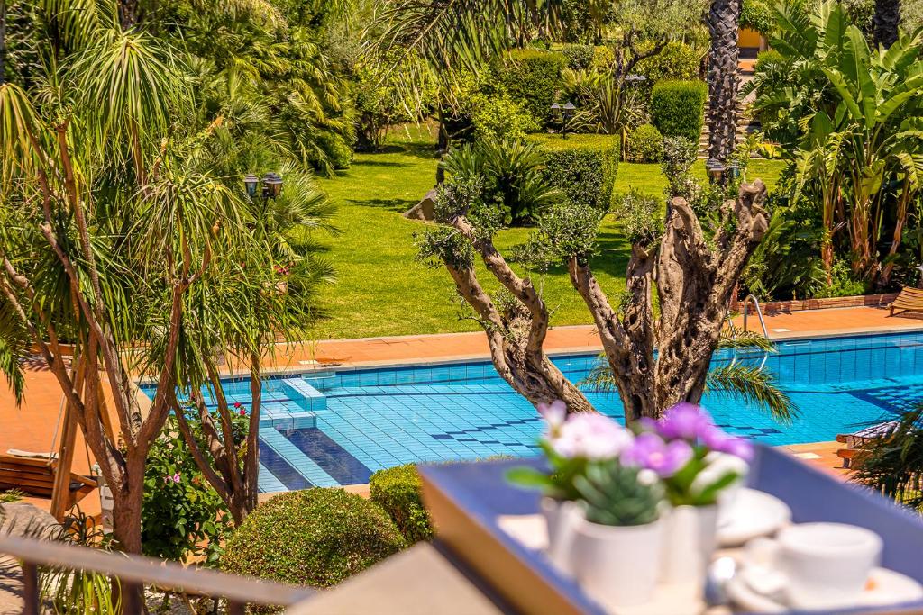 - une table avec des fleurs à côté de la piscine dans l'établissement Villa Gialla, à Aci Catena