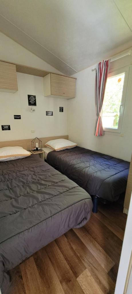 deux lits dans une chambre avec une fenêtre dans l'établissement Mobil-home le petit paradis Vendéen camping 3 étoiles 7km des plages, à Avrillé